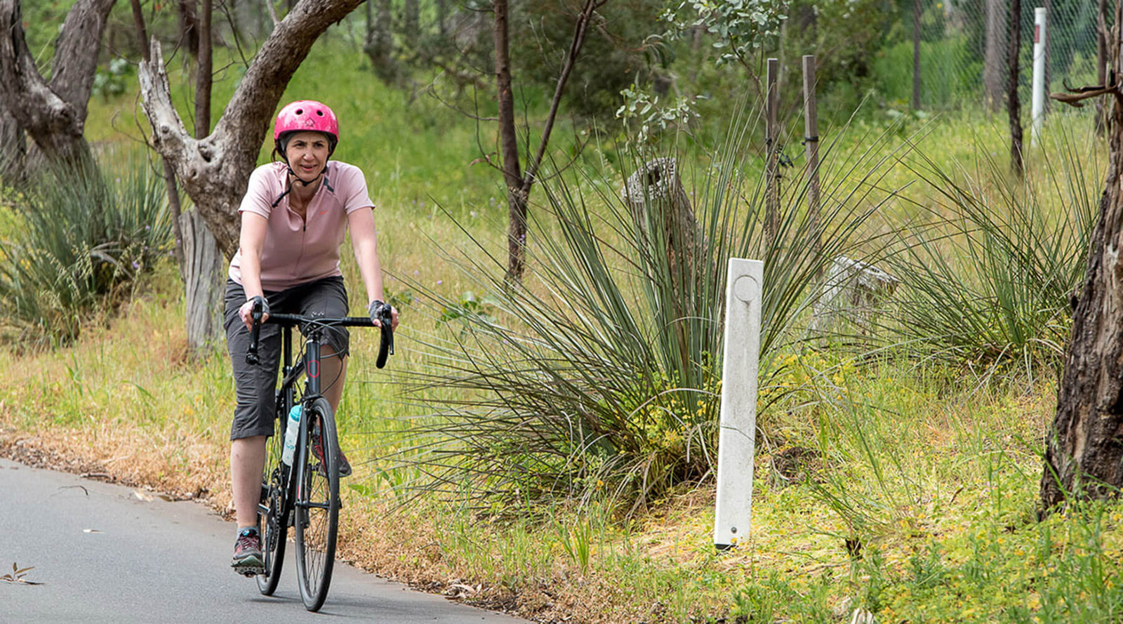Women road riding wearing a pick helmet with a sports headband underneath