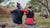 2 ladies sitting on a log facing away with running vests on wearing ponytail friendly sports headbands.
