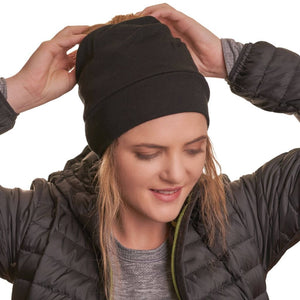 Women wearing ponytail friendly black ZQ merino wool beanie with hands adjusting ponytail