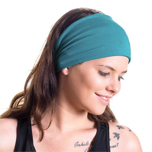 Women wearing wide teal bamboo sports headband while looking towards the right