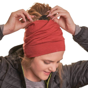 Women wearing ponytail friendly ZQ merino wool ochre coloured beanie with hands tightening ponytail