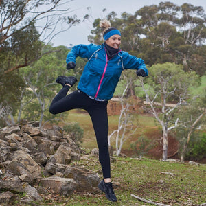 women jumping off a pile of rocks outside wearing blue-black-reversible winter headband