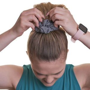 women wearing grey sports scrunchie with hands on ponytail looking down