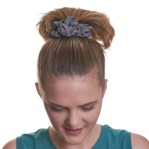 Women wearing grey sports scrunchie in a high ponytail gazing at the ground