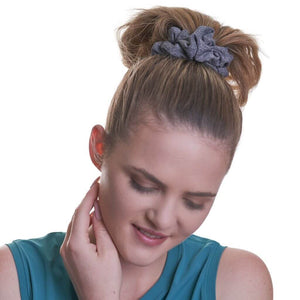Women wearing grey workout scrunchie looking down at the ground with left hand on neck