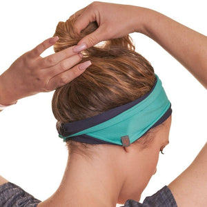 Back view of moisture wicking reversible sports headband while tying her her into a ponytail
