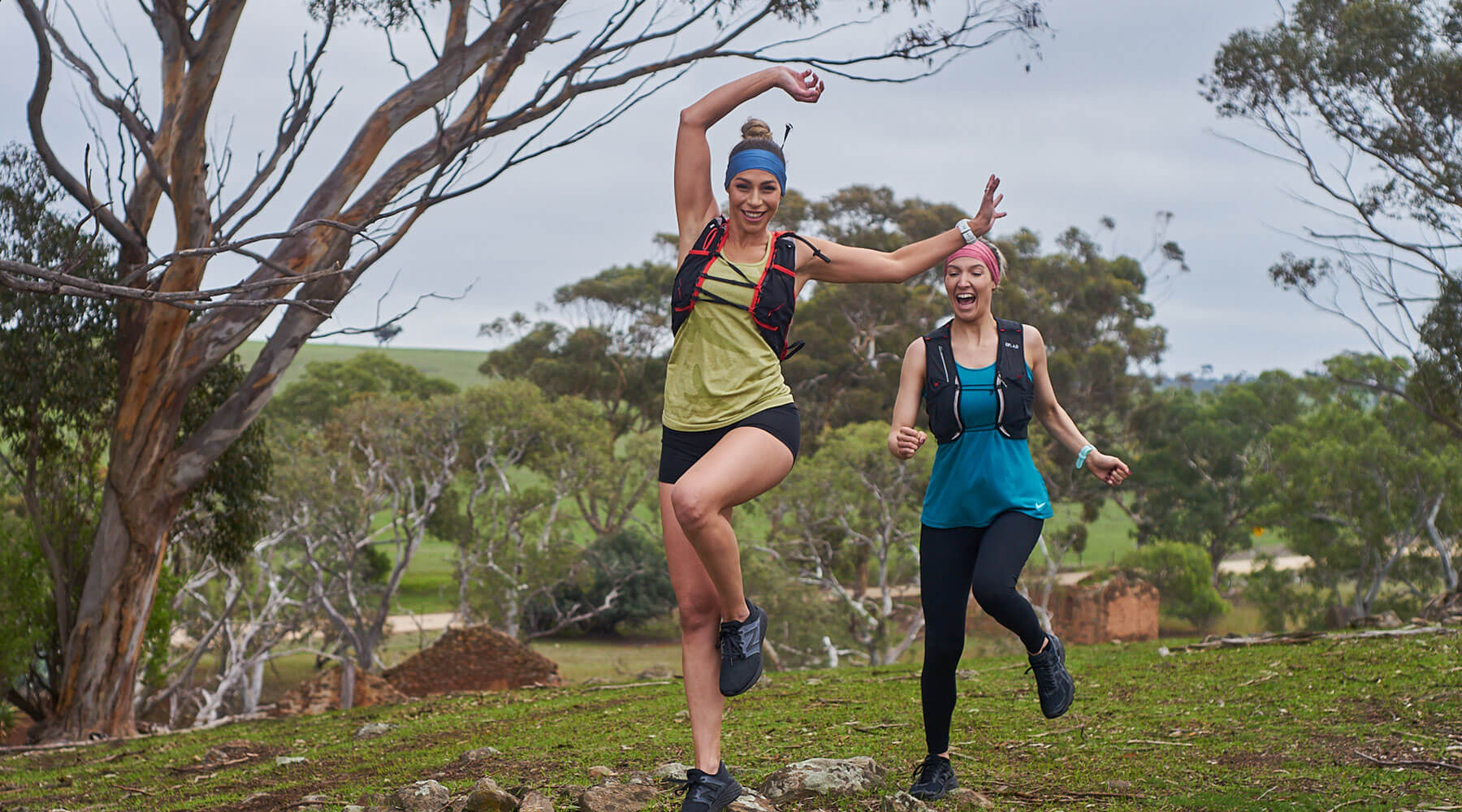 Two women trail running wearing light weight sports headbands in blue and red