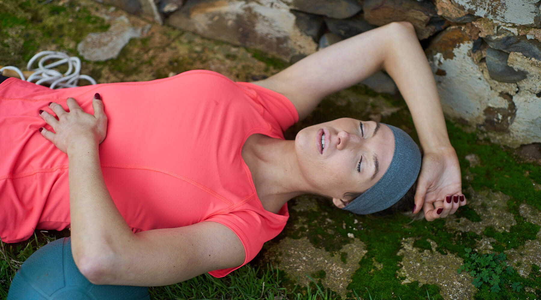 Women laying down after a work out wearing a grey light weight sports headband