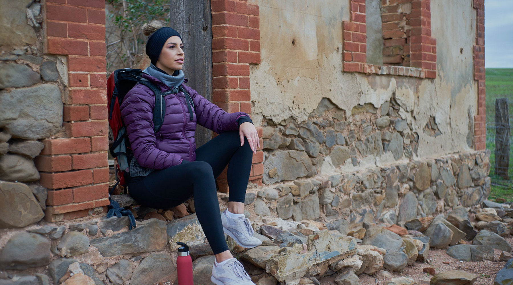 women resting outside a ruin gazing into the sky wearing winter ear wamers