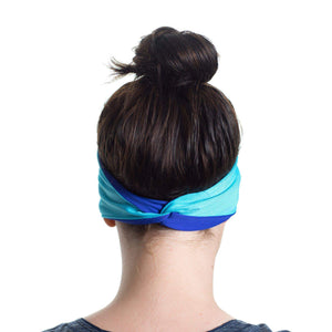 Back view of women wearing a aqua/purple reversible sports headband showcasing cross over.
