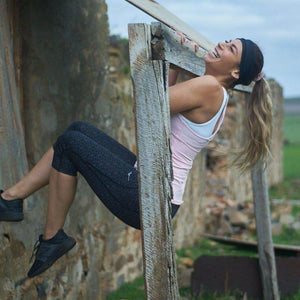 Women wearing black bamboo sports headband while doing a chin up outside while laughing