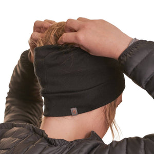 Side view of woman wearing a black merino beanie with hands adjusting ponytail