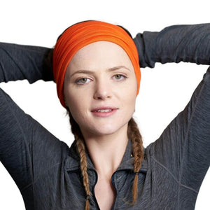 Women wearing brightly coloured bamboo yga headband with arms behind her head.