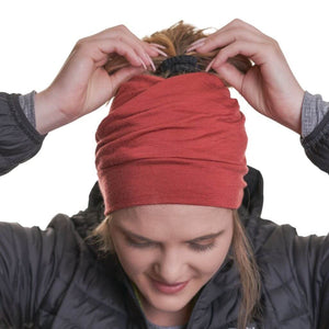 women tightening ponytail while wearing ochre coloured merino wool beanie