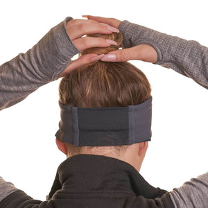 Back view of women wearing black and grey reversible winter headband with hands on top of her top knot
