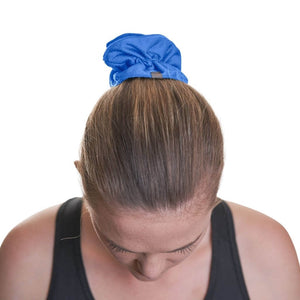 Women wearing blue sports scurnchie to Keep ponytail in place while gazing to the ground