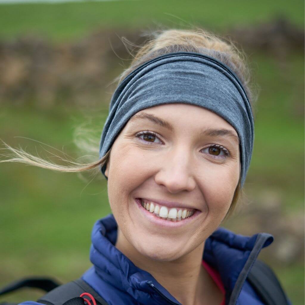 Head shot of women wearing a striped/grey merino wool reversible sports winter headband