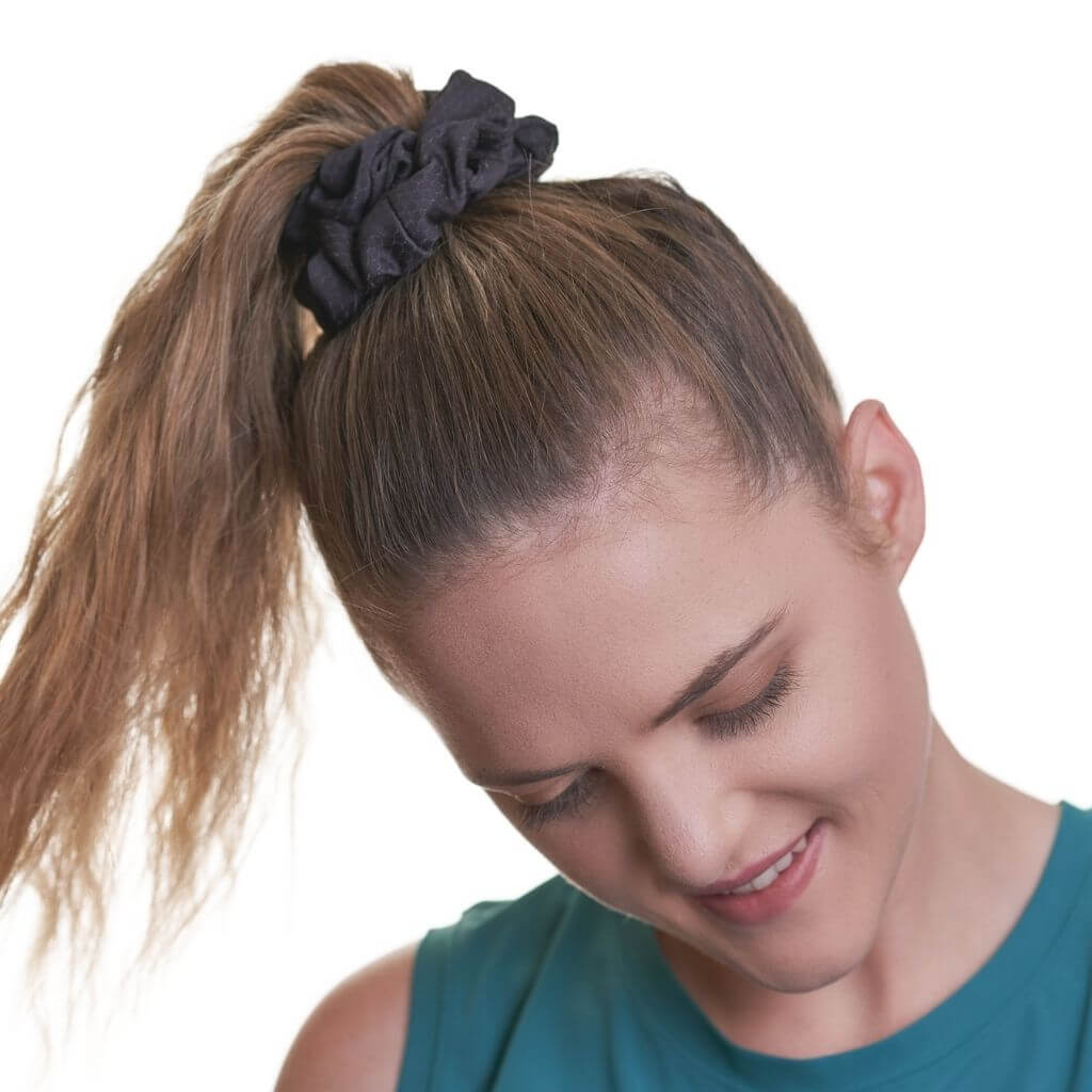 Women wearing black running scrunchie looking to the ground wearing an aqua sports top