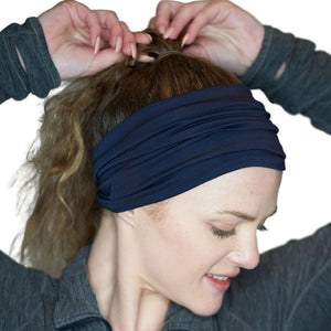 Women wearing wide navy blue bamboo sweatband with hands holding her ponytail