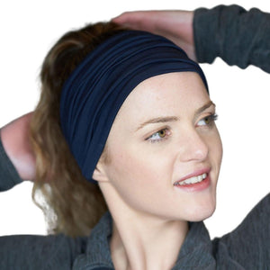 Women with hands on head staring sidewise wearing navy blue sports bamboo headband