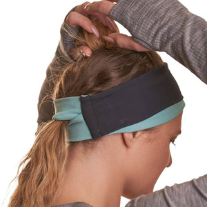 Side view of women wearing reversible black winter headband show casing the ponytail friendly slot in the back.