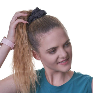 Women wearing black scrunchie made from offcuts while looking to the left with hand on ponytail